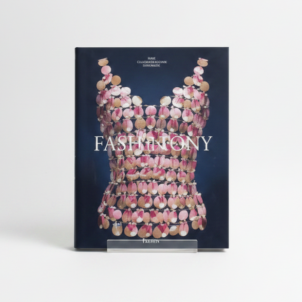 The Kyoto Costume Institute's 'Fashion History: From the 18th to the 20th Century' book cover by Taschen, featuring a dark navy blue background with a central graphic of a corset made of pink, gold, and silver circular elements.