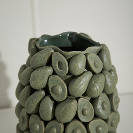 Decorative vase made of green ceramic stones with a smooth finish.